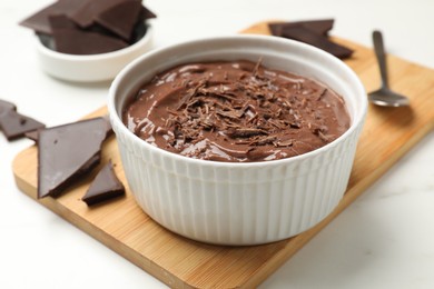 Photo of Tasty chocolate pudding in bowl served on white table, closeup