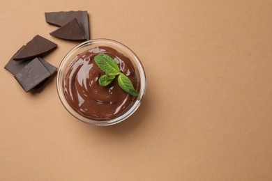 Photo of Delicious chocolate mousse in glass bowl on pale brown background, top view. Space for text