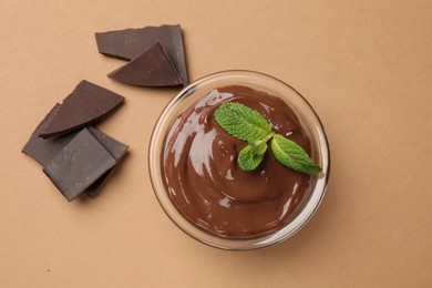 Photo of Delicious chocolate mousse in glass bowl on pale brown background, top view