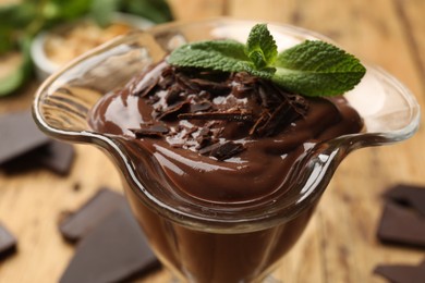 Photo of Delicious chocolate mousse in glass dessert bowl on wooden table, closeup