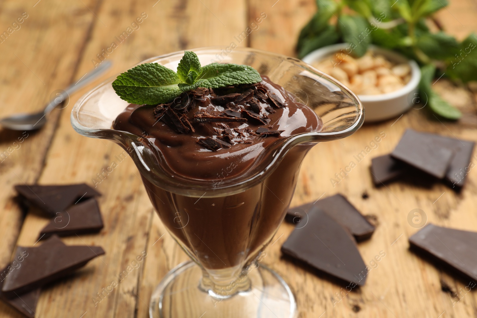 Photo of Delicious chocolate mousse in glass dessert bowl on wooden table, closeup