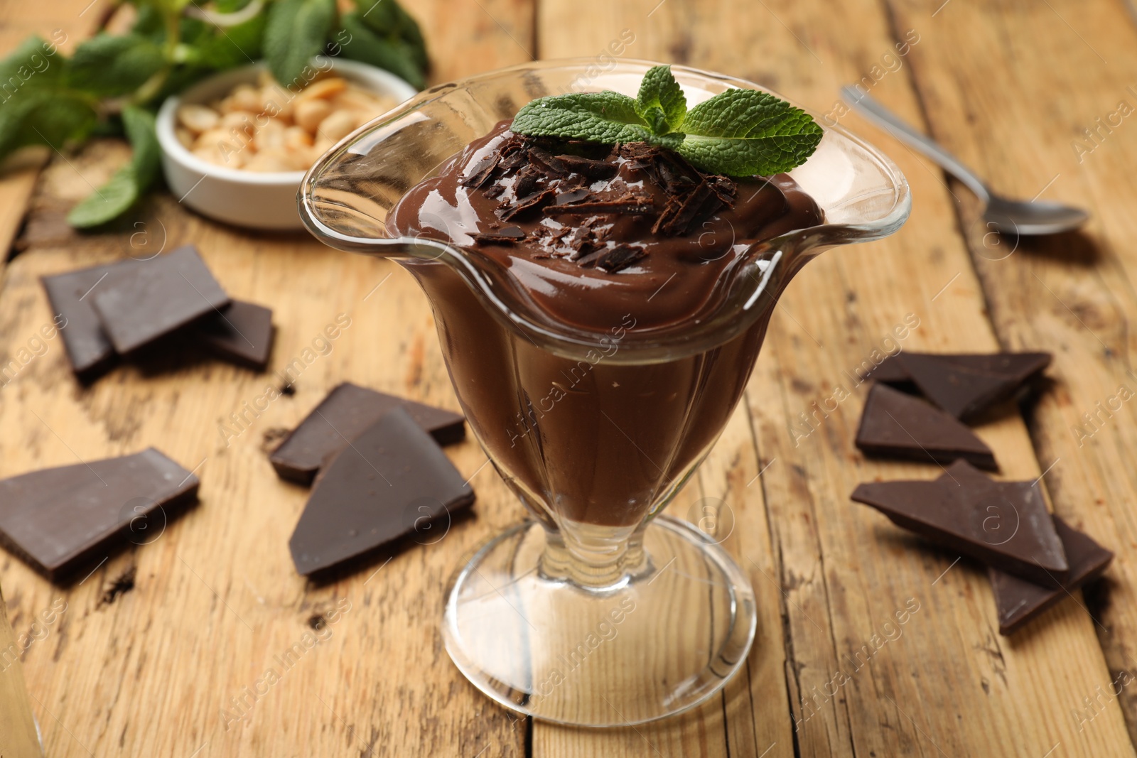 Photo of Delicious chocolate mousse in glass dessert bowl on wooden table, closeup