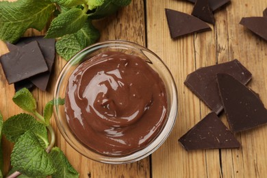 Photo of Delicious chocolate mousse in glass bowl on wooden table, flat lay