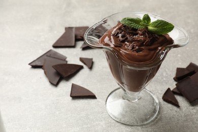 Photo of Delicious chocolate mousse in glass dessert bowl on grey table, closeup