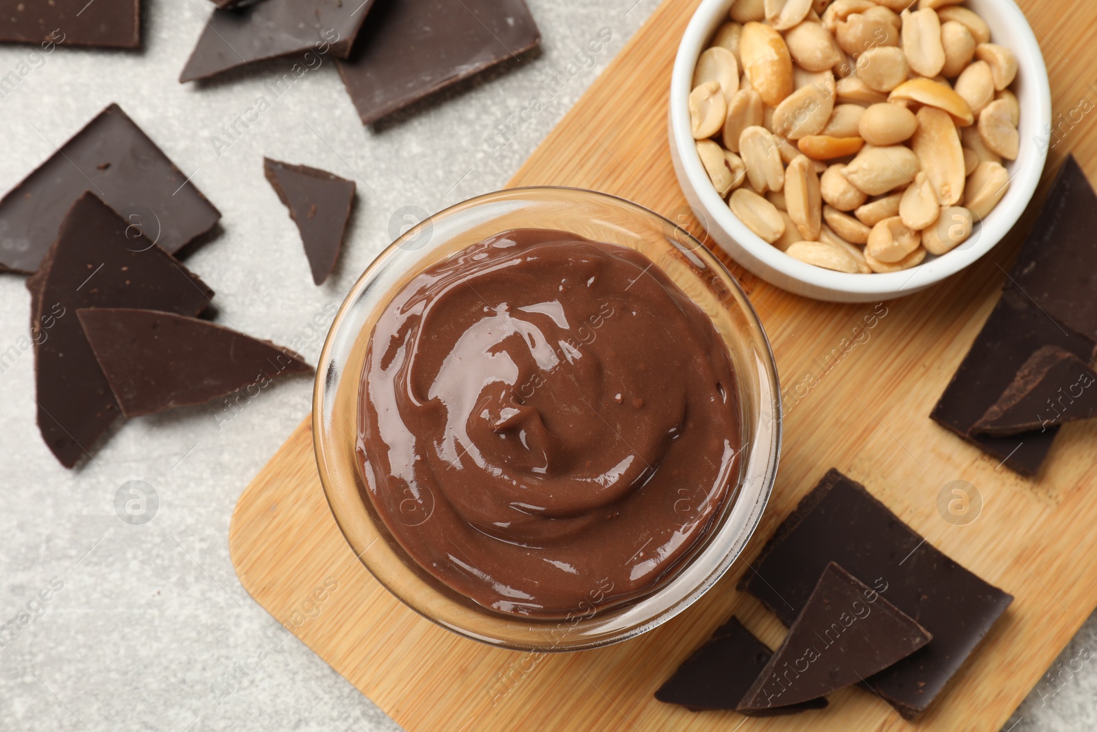 Photo of Delicious chocolate mousse in glass bowl and ingredients on grey table, flat lay