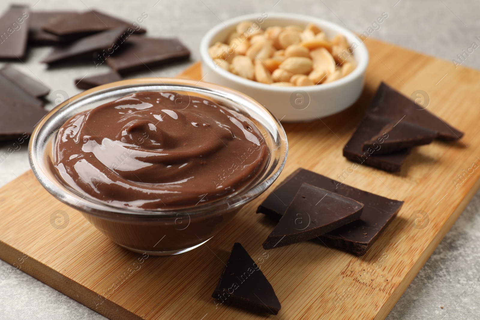 Photo of Delicious chocolate mousse in glass bowl and ingredients on grey table, closeup