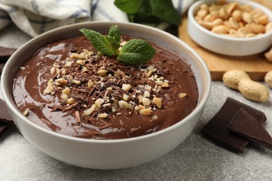 Delicious chocolate mousse in bowl grey table, closeup