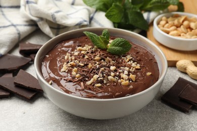 Photo of Delicious chocolate mousse in bowl grey table, closeup