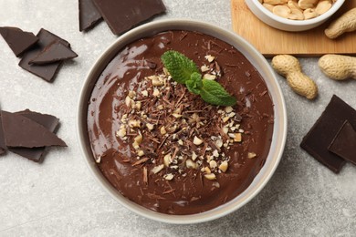 Photo of Delicious chocolate mousse in bowl and ingredients on grey table, flat lay