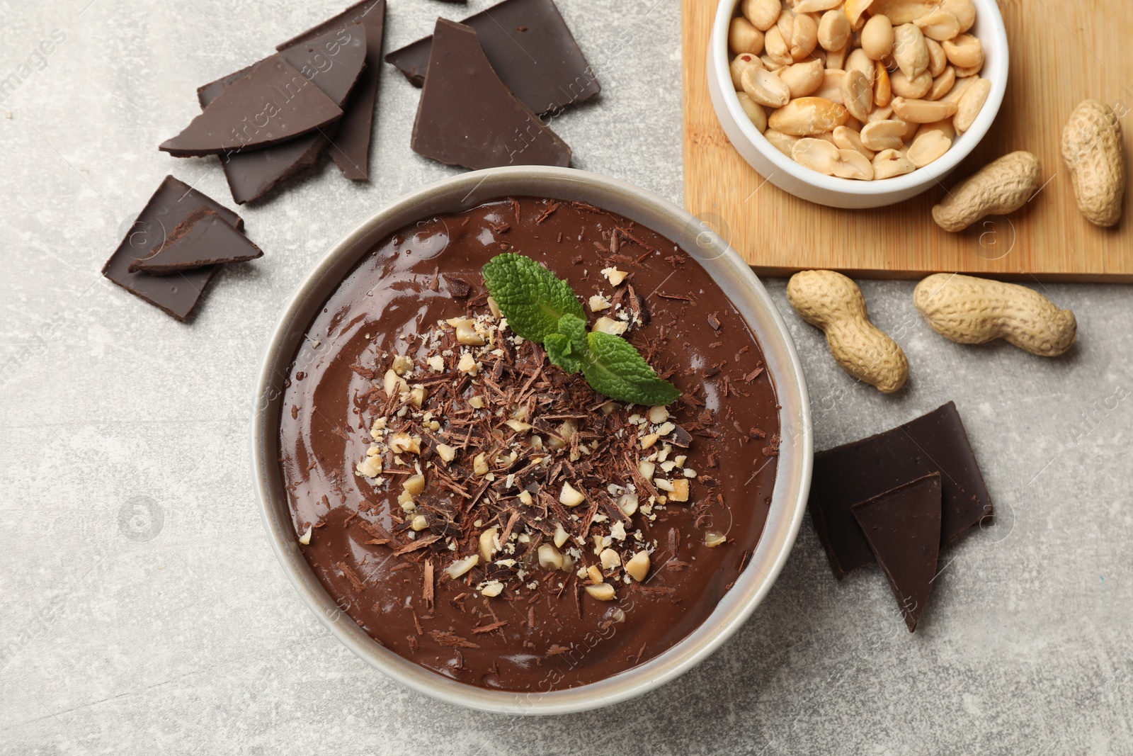 Photo of Delicious chocolate mousse in bowl and ingredients on grey table, flat lay