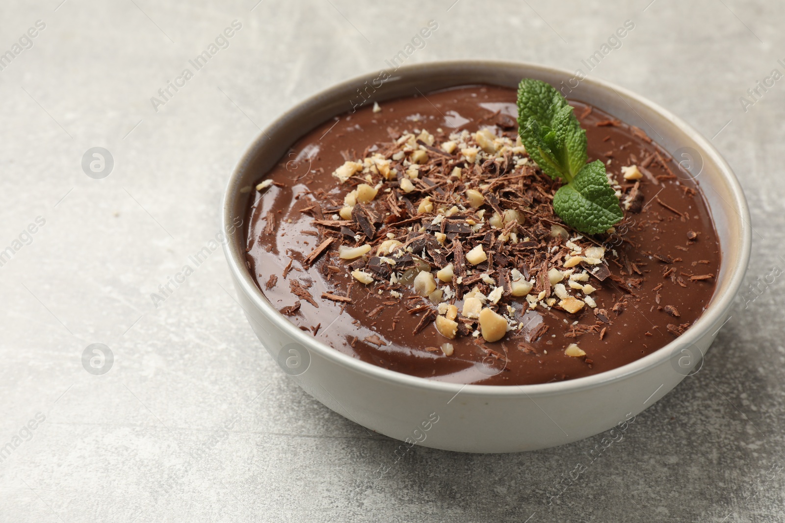 Photo of Delicious chocolate mousse in bowl on grey table, closeup. Space for text