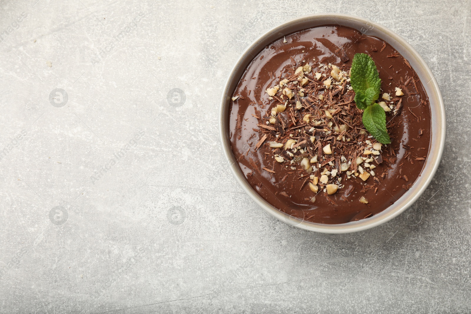 Photo of Delicious chocolate mousse in bowl on grey table, top view. Space for text