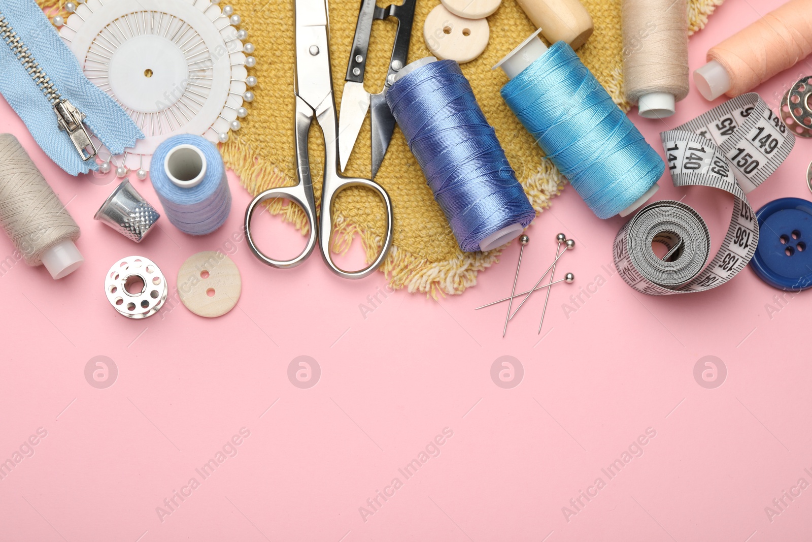 Photo of Different sewing supplies on pink background, flat lay. Space for text