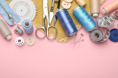 Photo of Different sewing supplies on pink background, flat lay. Space for text