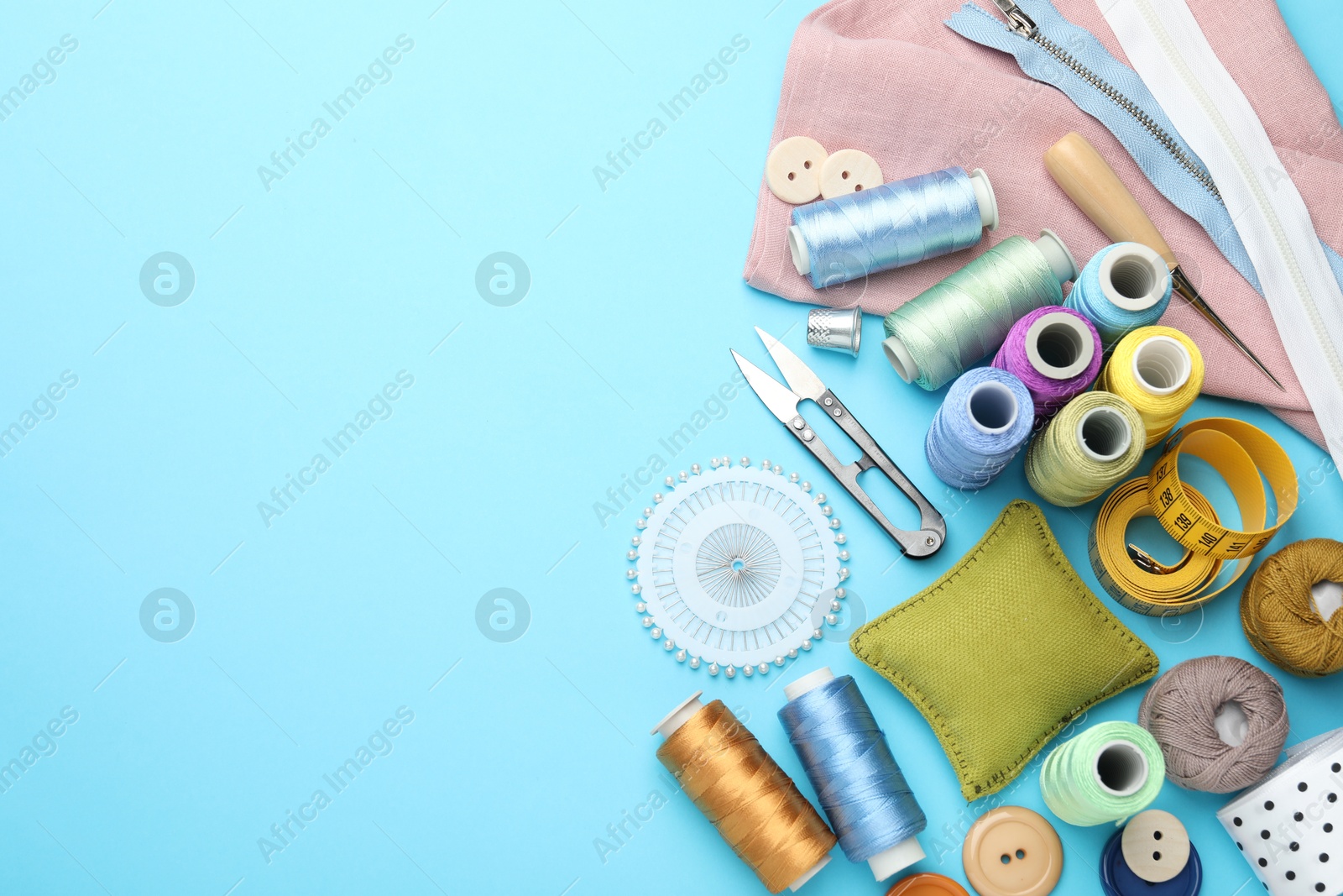 Photo of Different sewing supplies on light blue background, flat lay. Space for text