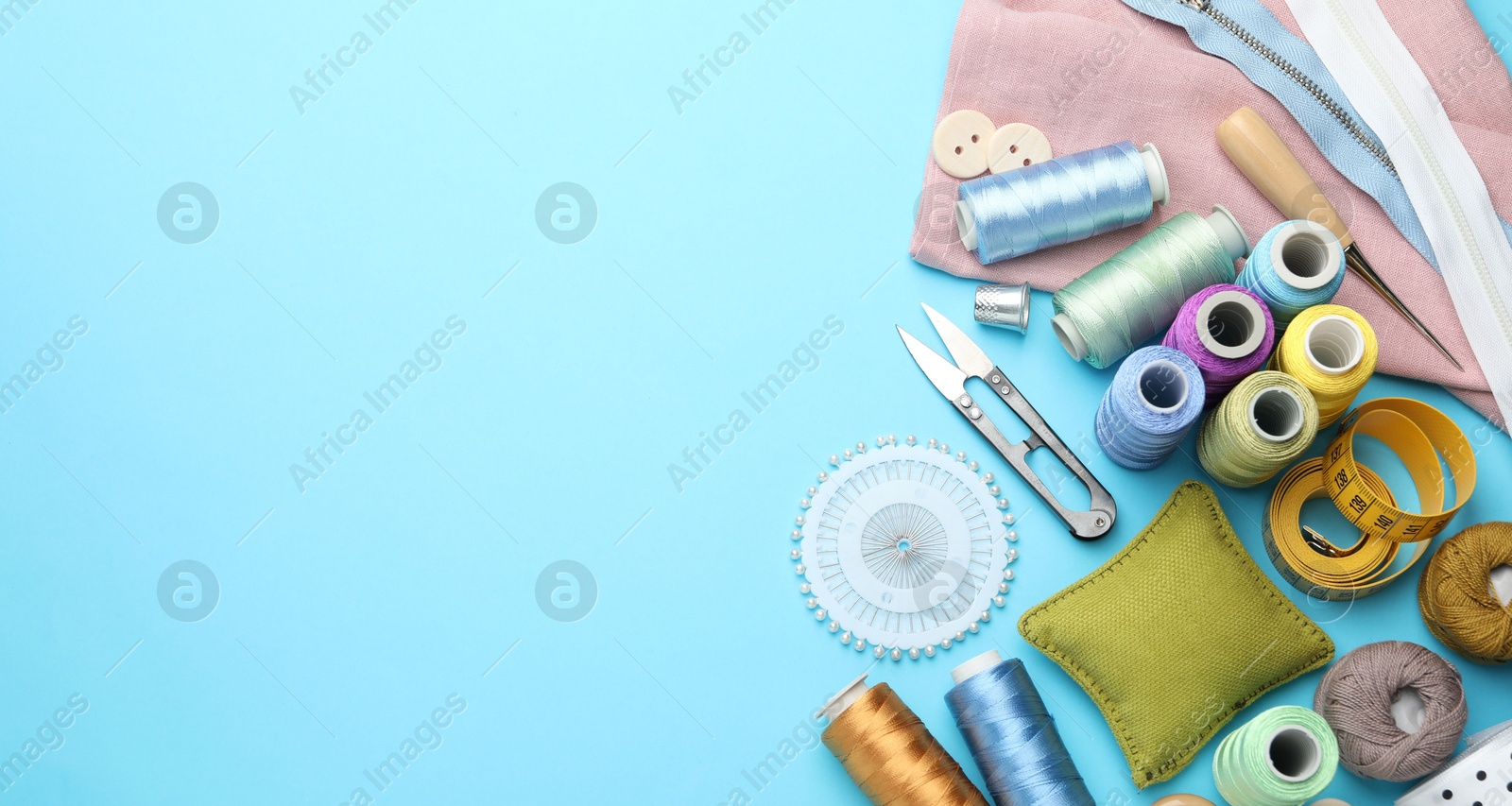 Photo of Different sewing supplies on light blue background, flat lay. Space for text