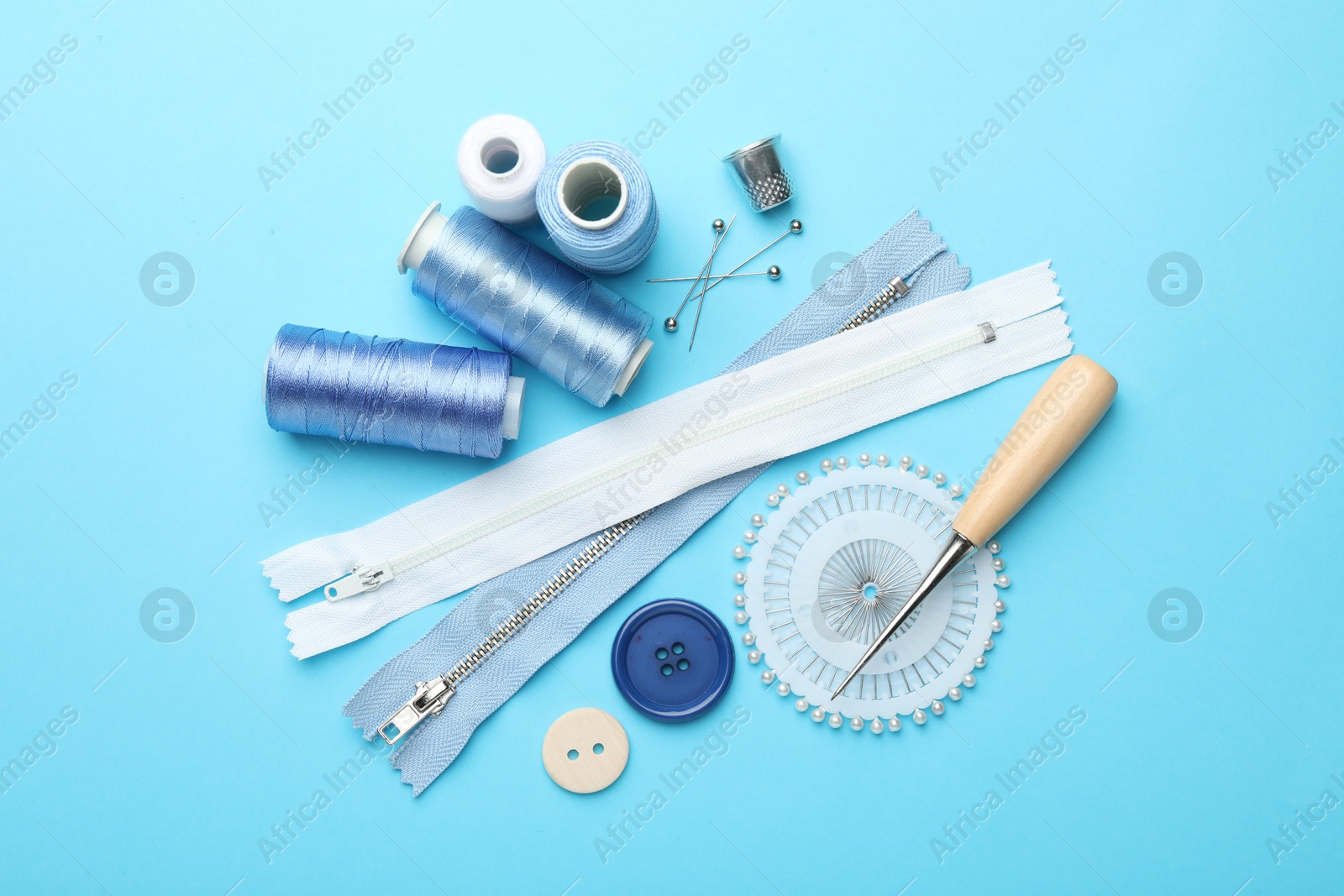 Photo of Different sewing supplies on light blue background, flat lay