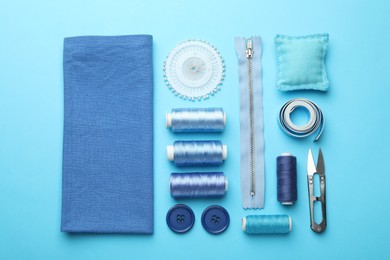 Photo of Different sewing supplies on light blue background, flat lay