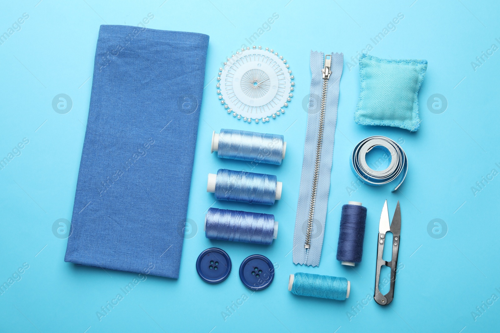 Photo of Different sewing supplies on light blue background, flat lay