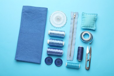 Photo of Different sewing supplies on light blue background, flat lay