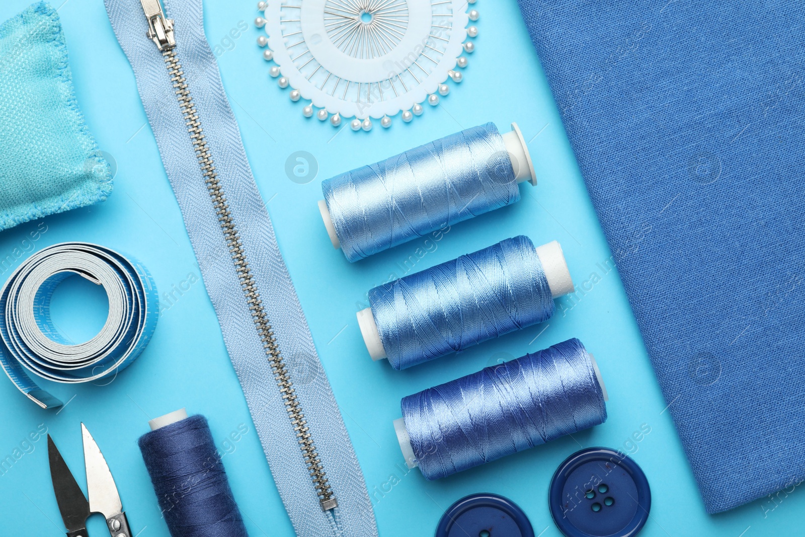 Photo of Different sewing supplies on light blue background, flat lay