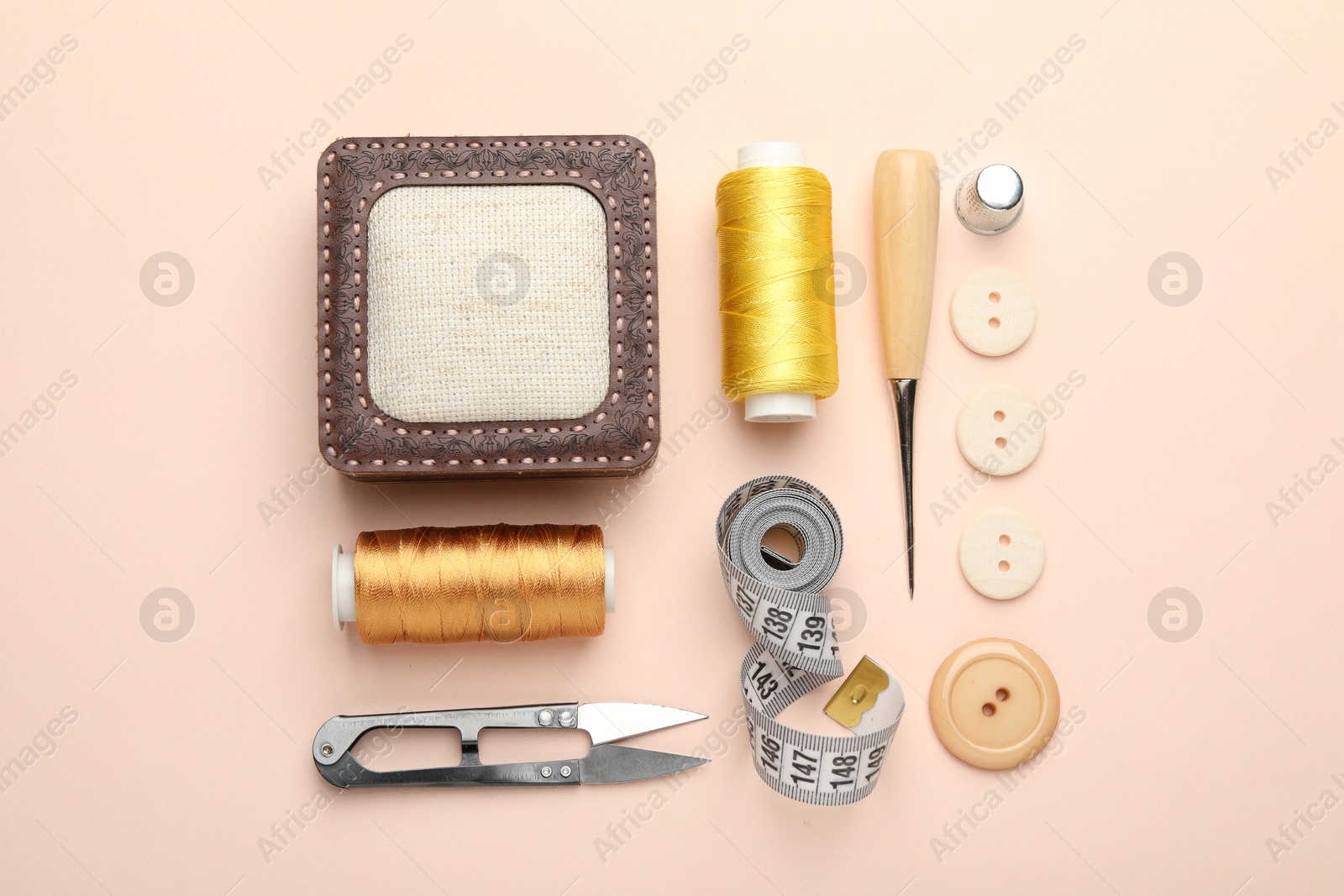 Photo of Different sewing supplies on light pink background, flat lay