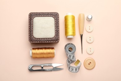 Photo of Different sewing supplies on light pink background, flat lay