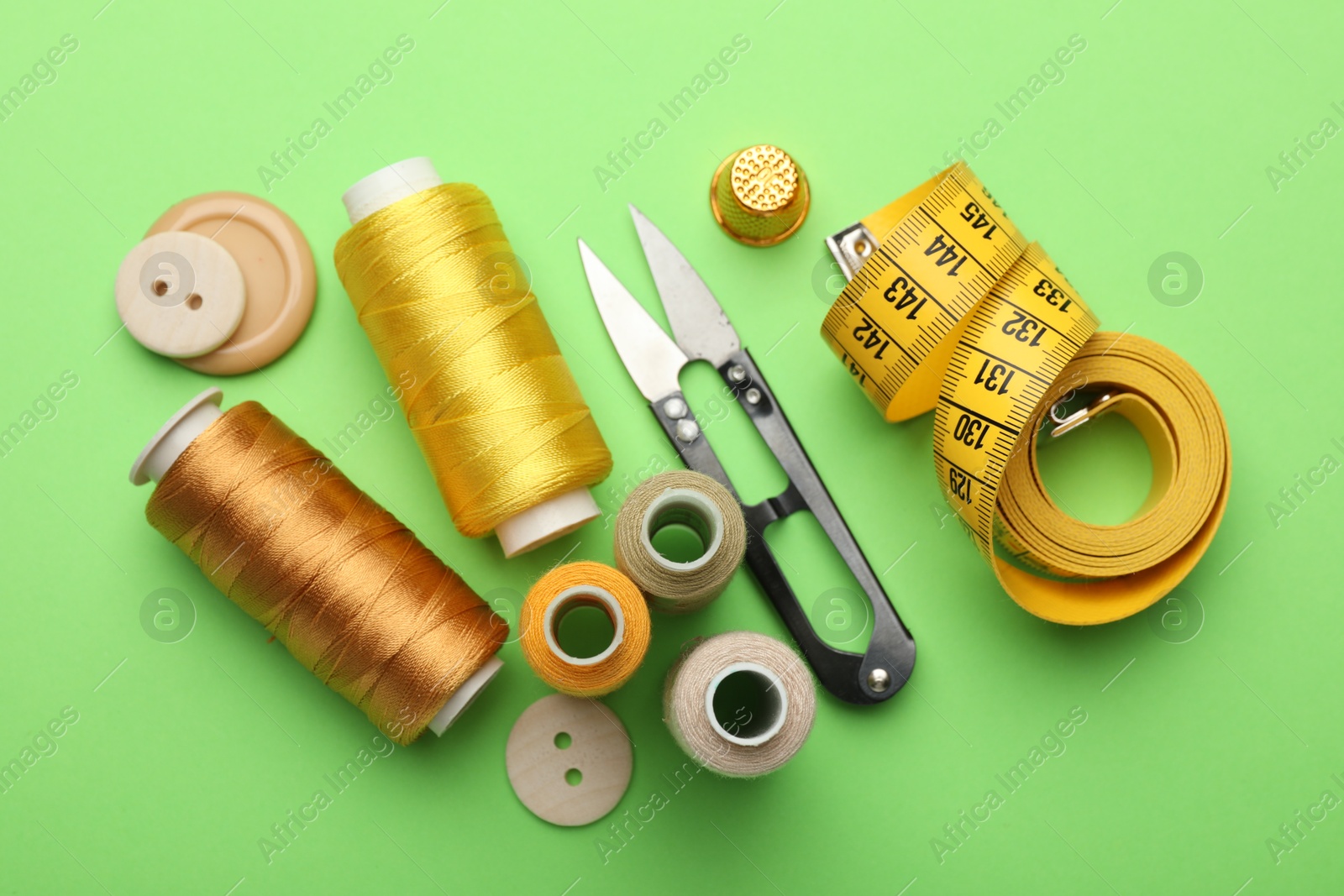 Photo of Different sewing supplies on green background, flat lay