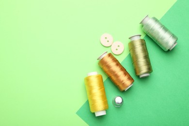 Photo of Different sewing supplies on green background, flat lay. Space for text