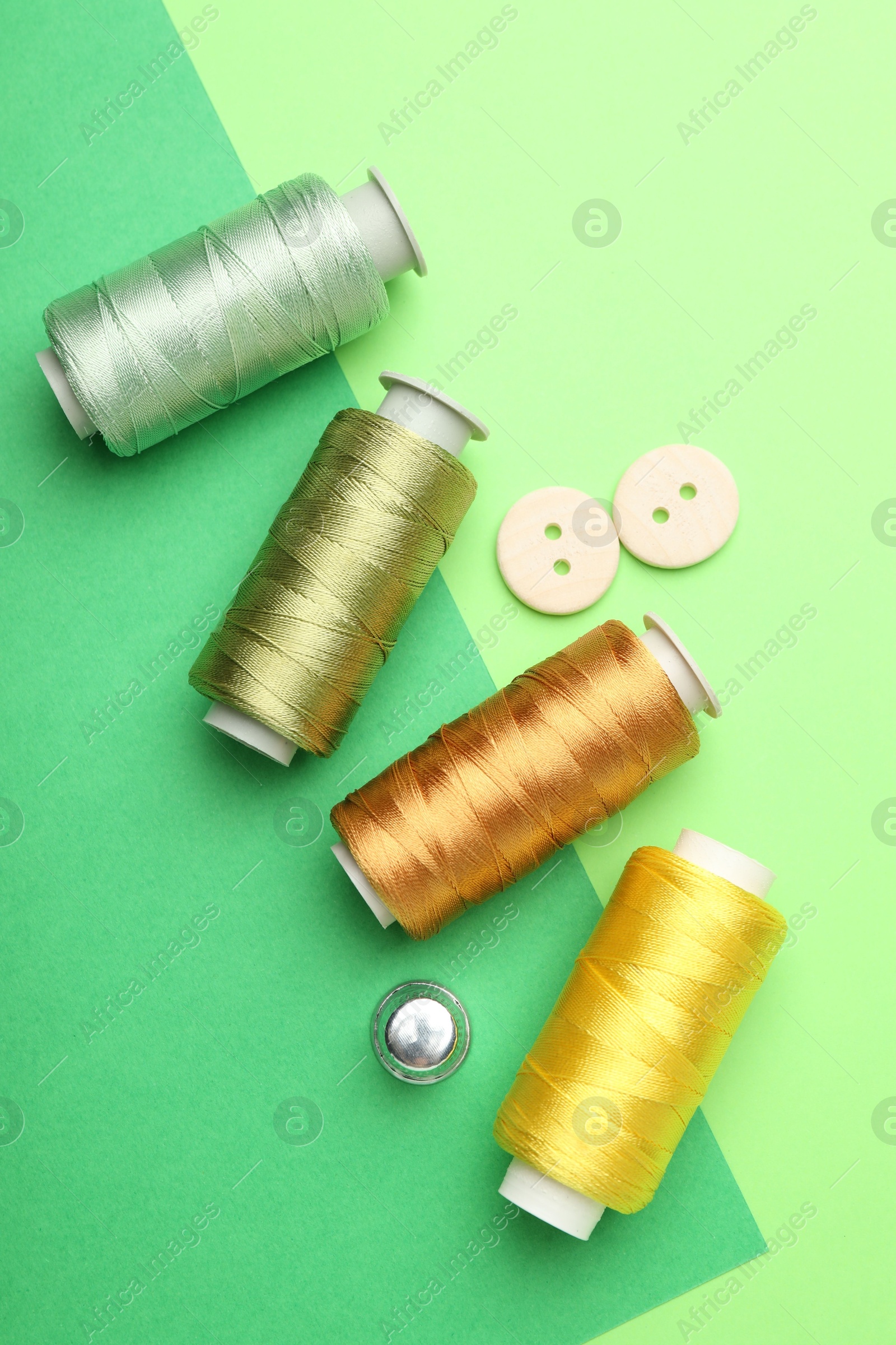 Photo of Different sewing supplies on green background, flat lay