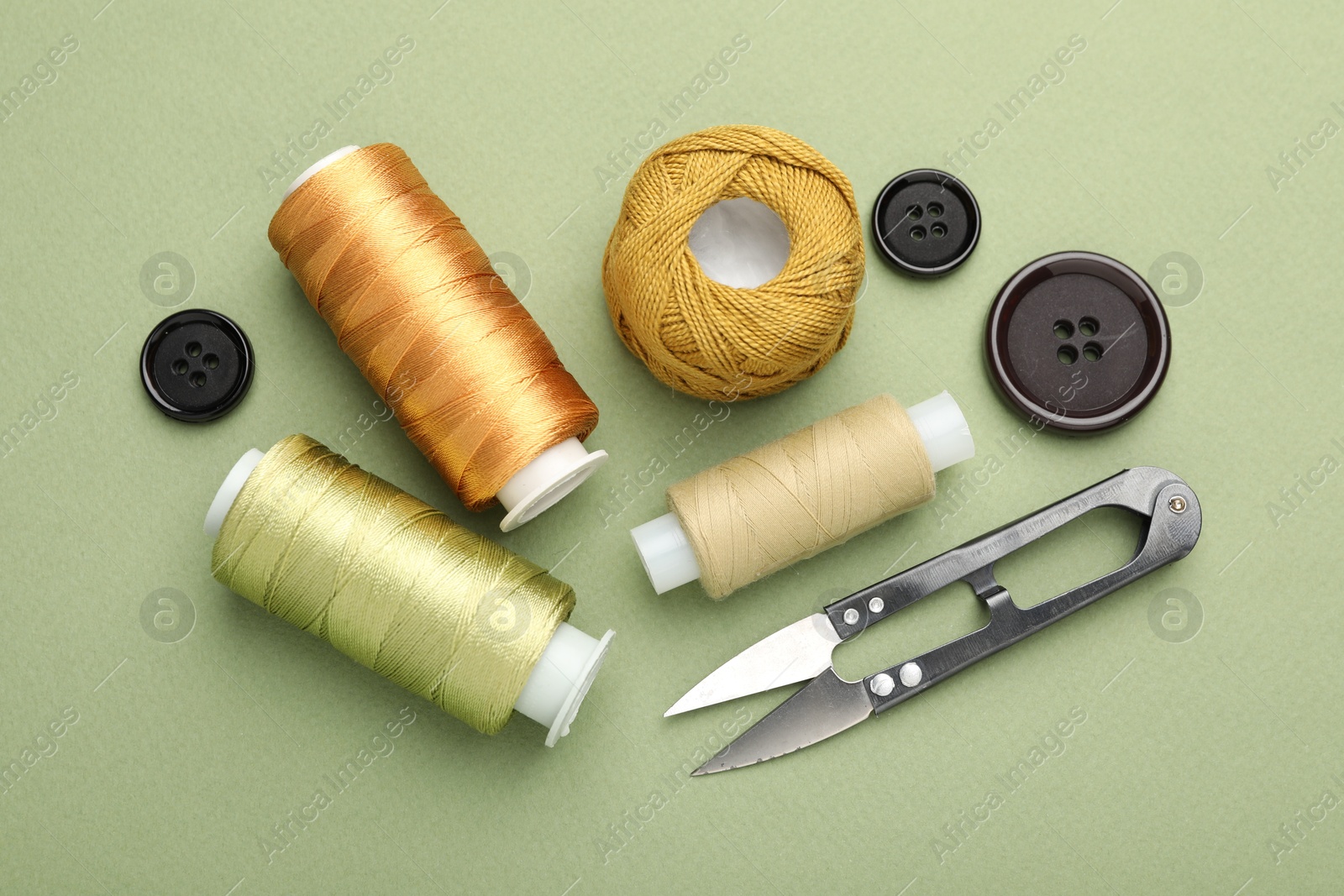 Photo of Different sewing supplies on olive background, flat lay