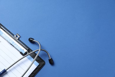 Photo of Stethoscope and medical card form on blue background, top view. Space for text