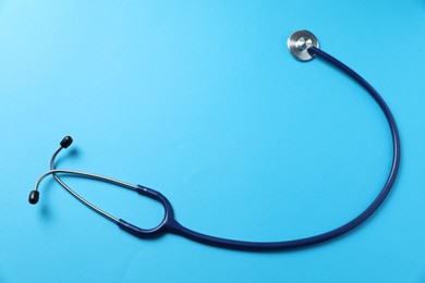 Photo of Stethoscope on light blue background, top view