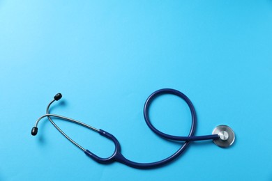 Photo of Stethoscope on light blue background, top view. Space for text