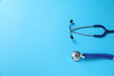 Photo of Stethoscope on light blue background, top view. Space for text