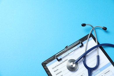 Photo of Stethoscope and medical card form on light blue background, top view. Space for text