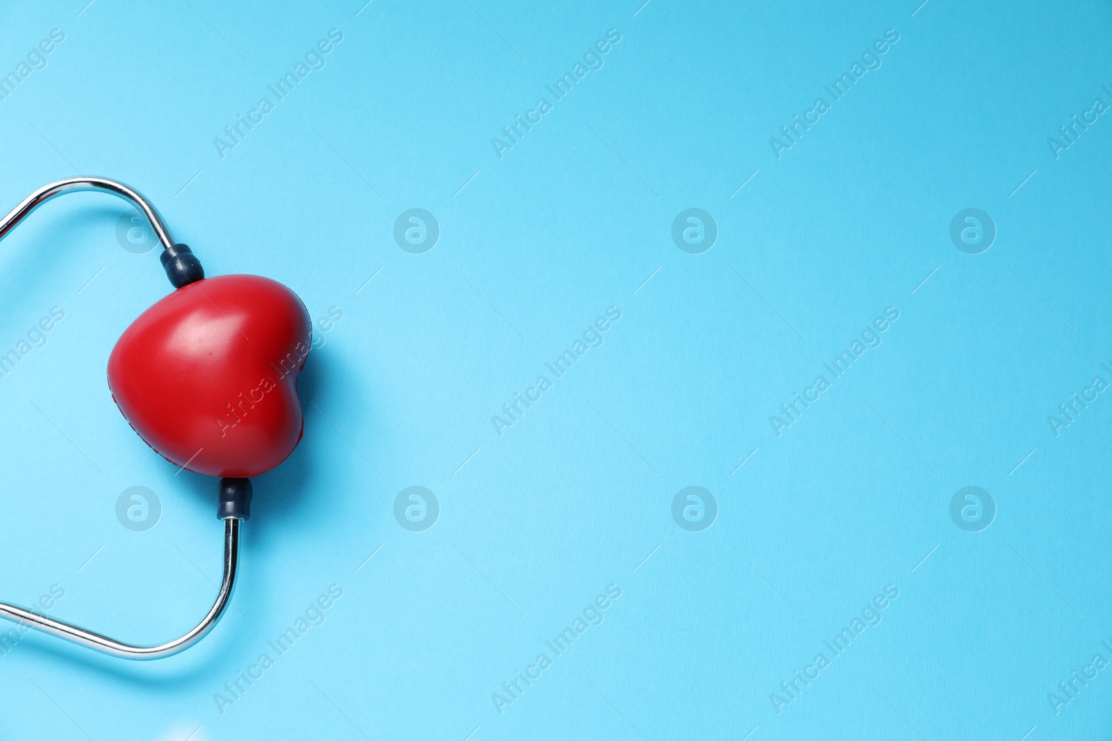 Stethoscope and red decorative heart on light blue background, top view. Space for text Photo of Stethoscope and red decorative heart on light blue background, top view. Space for text
