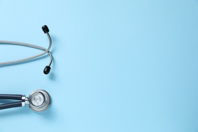 Photo of Stethoscope on light blue background, top view. Space for text