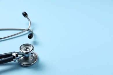 Photo of Stethoscope on light blue background, closeup. Space for text