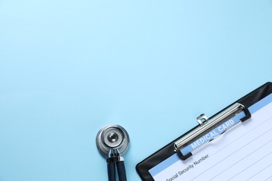 Photo of Stethoscope and medical card form on light blue background, top view. Space for text