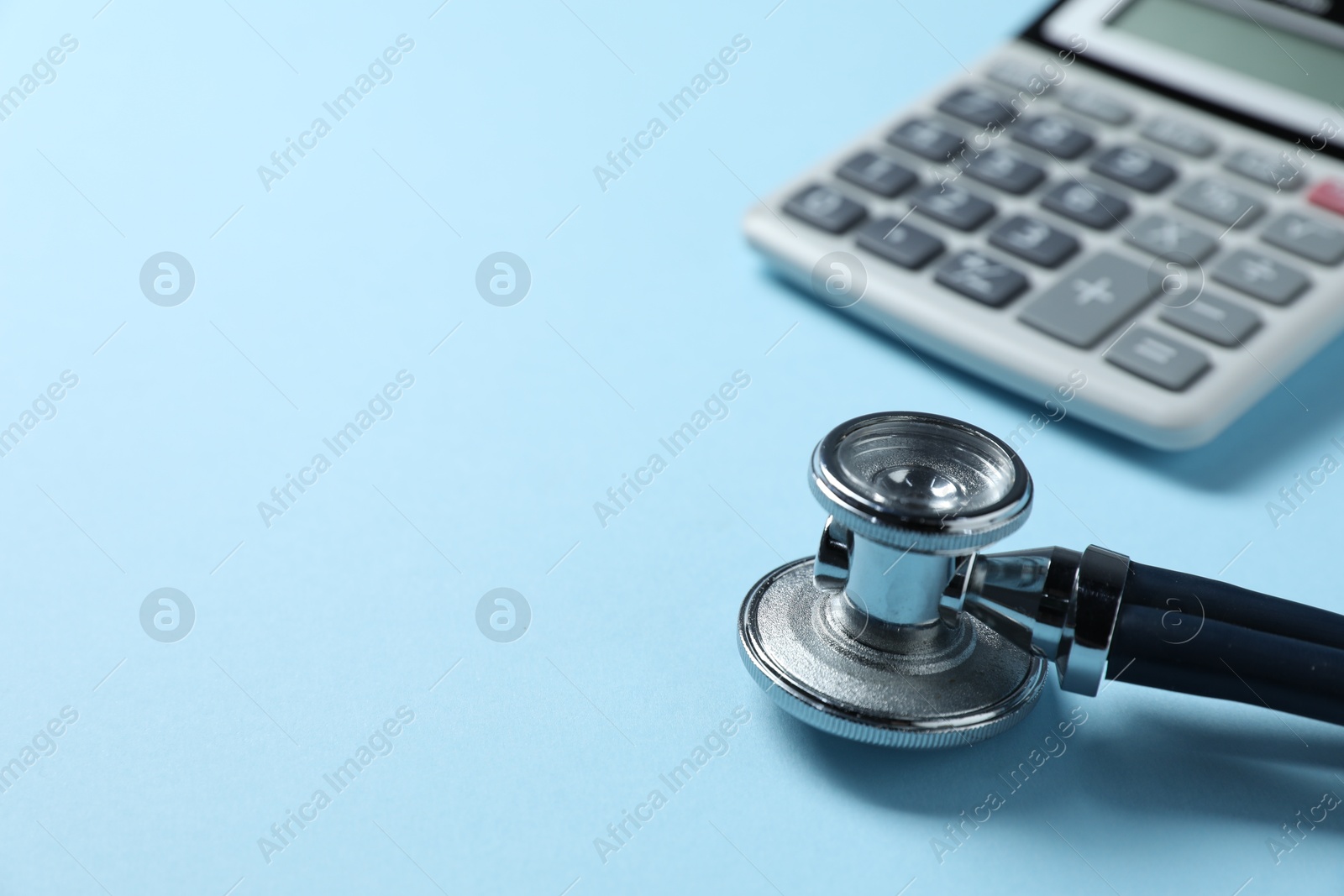 Stethoscope and calculator on light blue background, closeup. Space for text Photo of Stethoscope and calculator on light blue background, closeup. Space for text