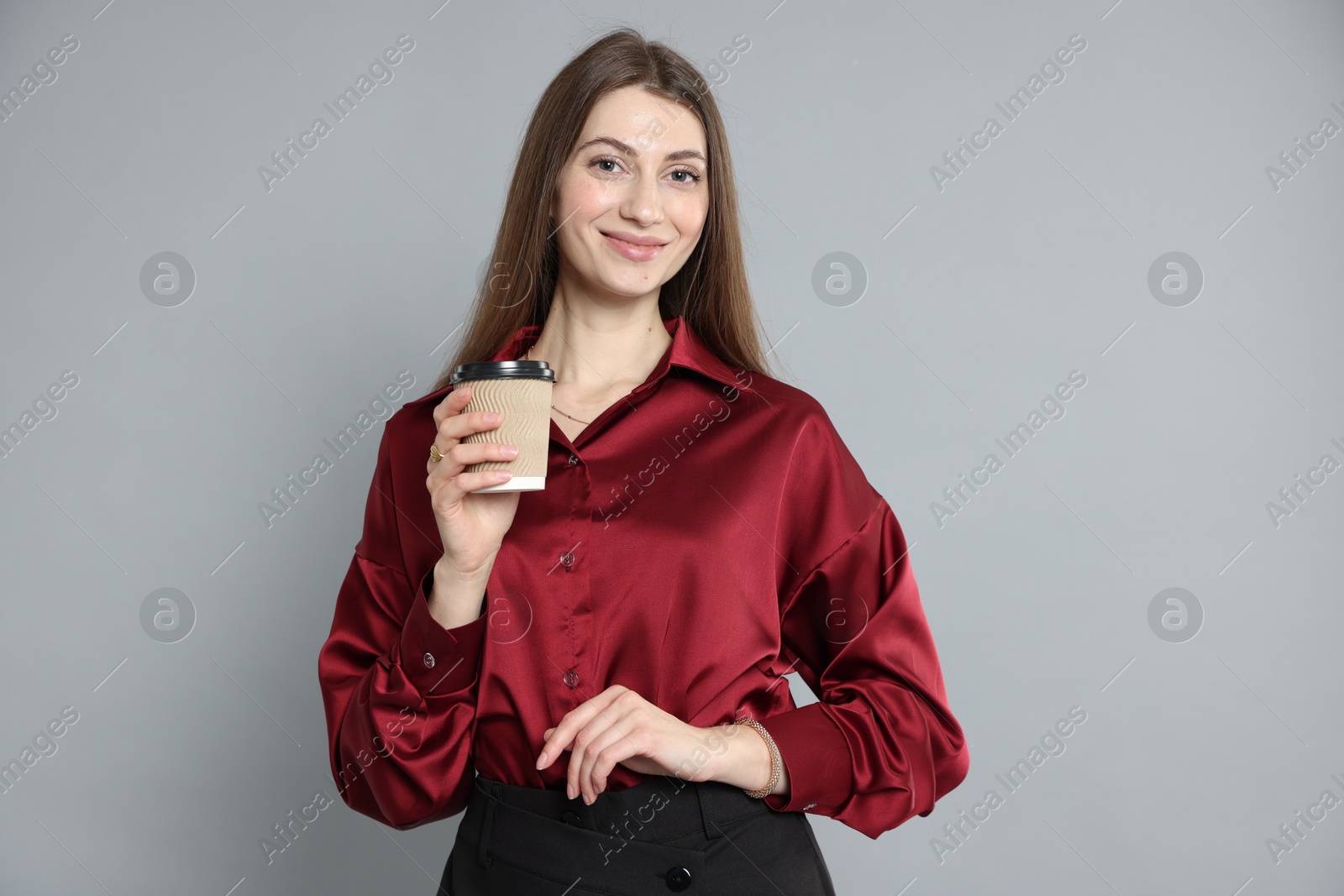 Photo of Beautiful woman in stylish outfit with cup of coffee on grey background