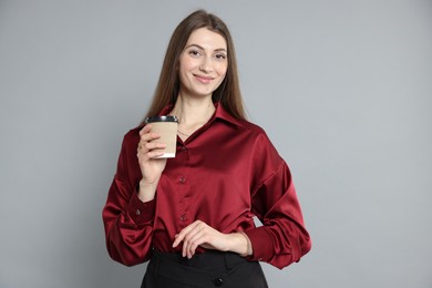 Photo of Beautiful woman in stylish outfit with cup of coffee on grey background