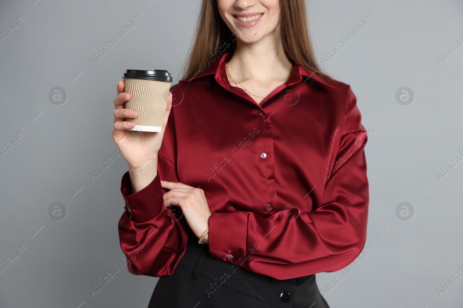 Photo of Beautiful woman in stylish outfit with cup of coffee on grey background, closeup