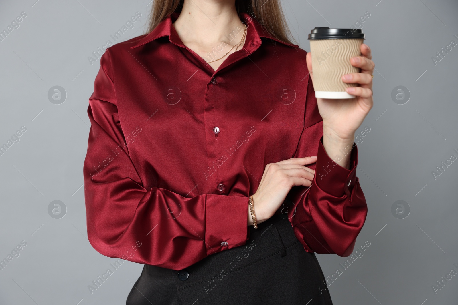 Photo of Beautiful woman in stylish outfit with cup of coffee on grey background, closeup