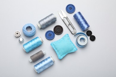 Photo of Different sewing supplies on light grey background, flat lay