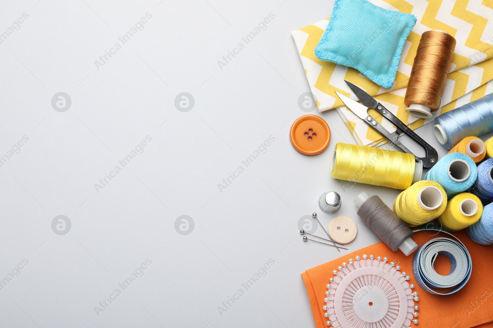 Photo of Different sewing supplies on light grey background, flat lay. Space for text