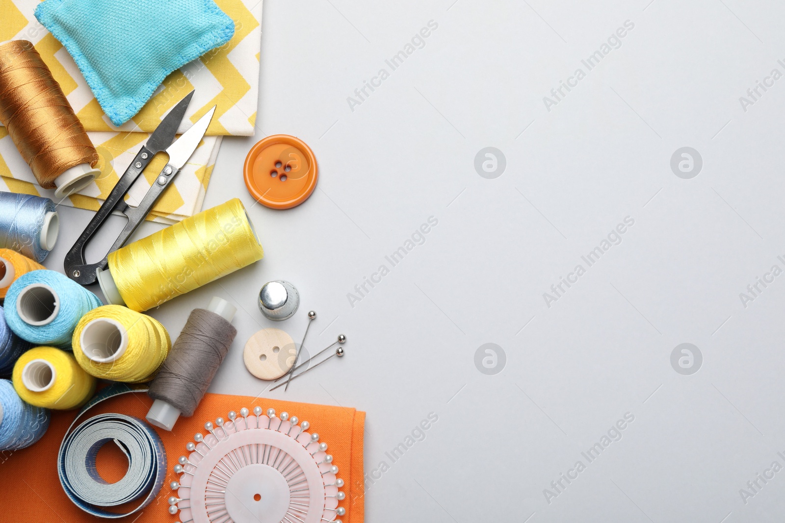 Photo of Different sewing supplies on light grey background, flat lay. Space for text