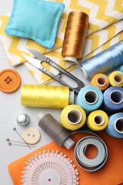 Photo of Different sewing supplies on light grey background, flat lay