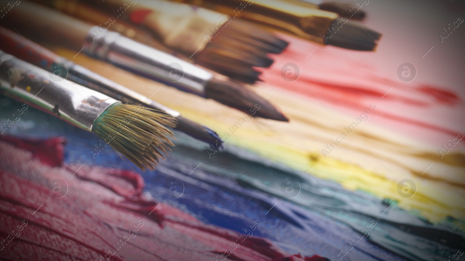 Image of Artist's canvas with many brushes and mixed paints, closeup